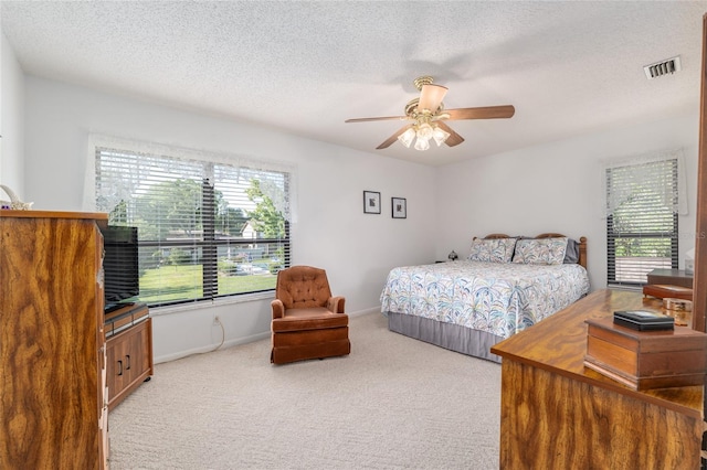 3815 NE 17th Street Cir, Ocala, FL 34470 - bedroom with light colored carpet, multiple windows, a textured ceiling, baseboards, and a ceiling fan