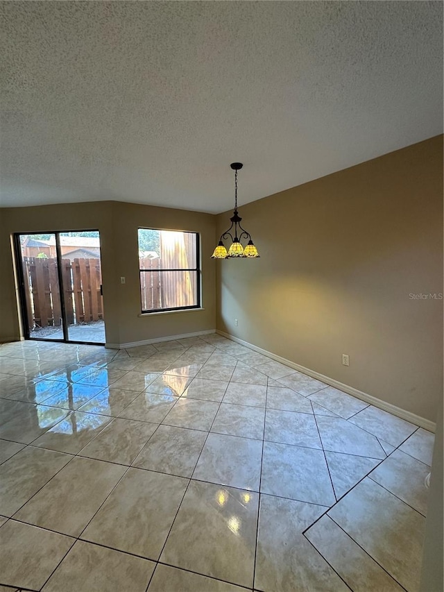 spare room with a textured ceiling, baseboards, and light tile patterned floors