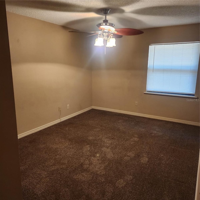 unfurnished room with a ceiling fan, dark colored carpet, a textured ceiling, and baseboards