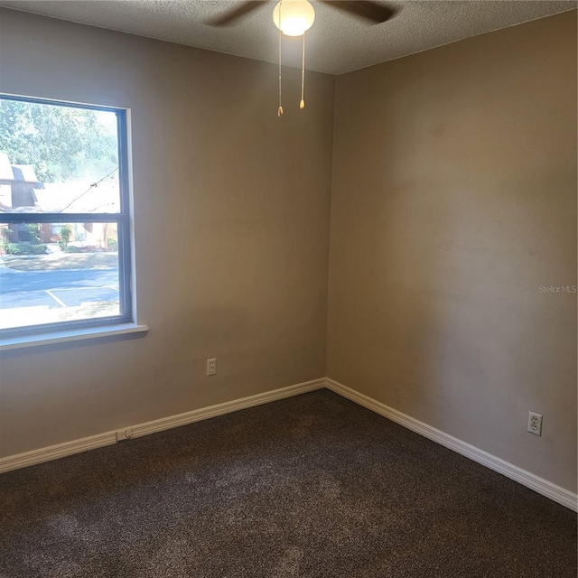 unfurnished room featuring dark carpet, ceiling fan, and baseboards