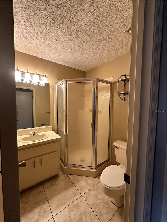 bathroom with vanity, tile patterned flooring, a stall shower, toilet, and a textured ceiling
