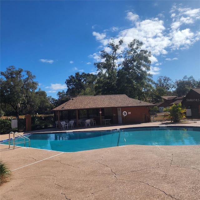 community pool featuring fence and a patio