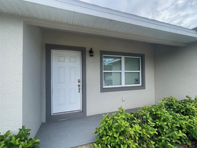 entrance to property featuring stucco siding and a porch