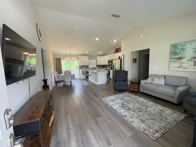 living area with a chandelier, dark wood-type flooring, high vaulted ceiling, and recessed lighting