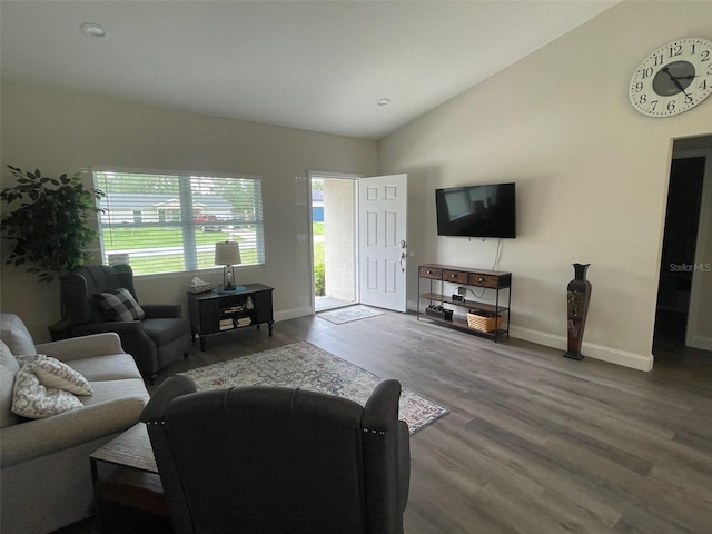 living area with wood finished floors, vaulted ceiling, and baseboards
