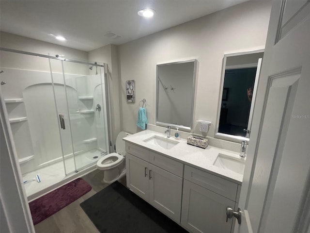 bathroom featuring a shower stall, double vanity, toilet, and recessed lighting
