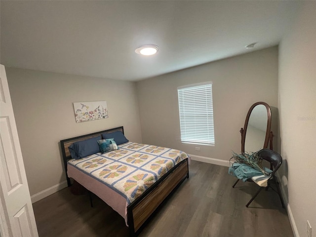 bedroom with baseboards and dark wood-type flooring