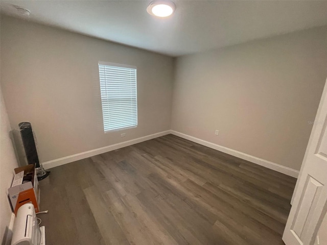 spare room featuring dark wood-style floors and baseboards