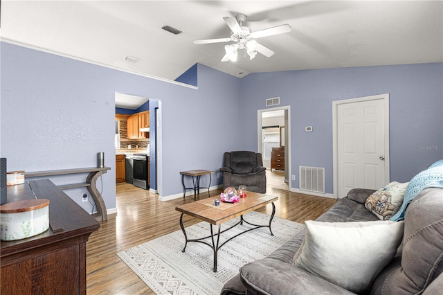 living room featuring vaulted ceiling, ceiling fan, light wood finished floors, and baseboards