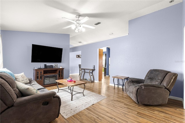 living room featuring light wood-style floors, baseboards, a ceiling fan, and lofted ceiling