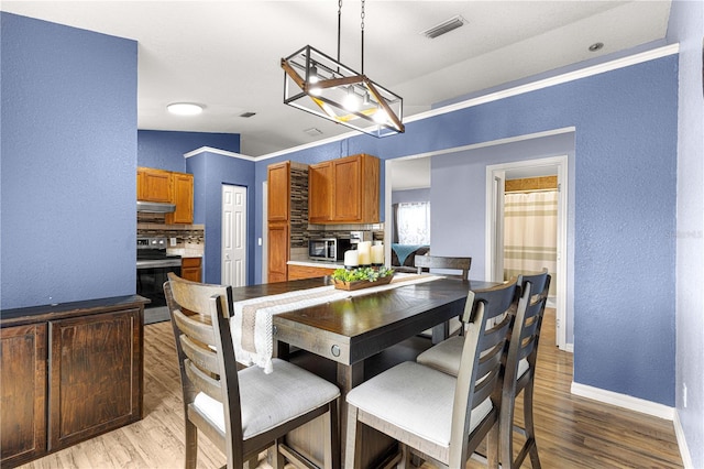 dining area with a textured wall, light wood-style flooring, and baseboards