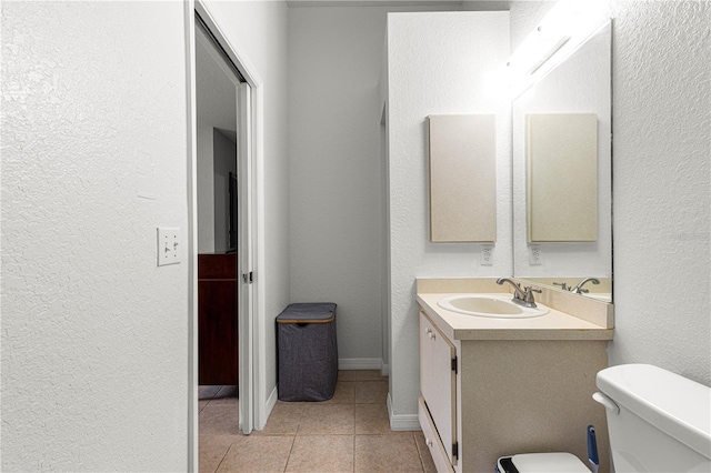 bathroom with tile patterned flooring, a textured wall, vanity, and toilet