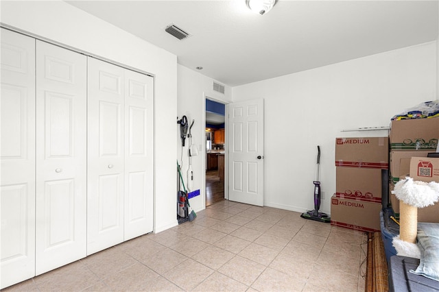 bedroom featuring a closet, light tile patterned floors, and baseboards