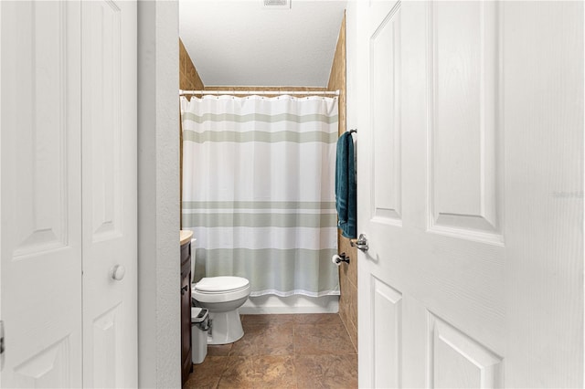 full bathroom with toilet, curtained shower, stone finish floors, and vanity