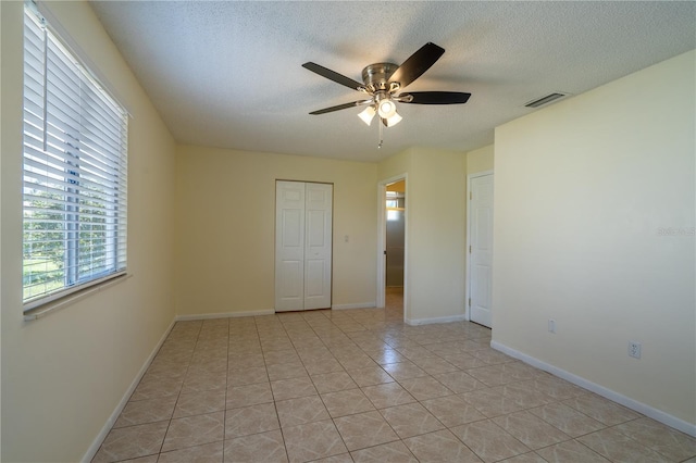 8463 SW 108th Pl, Ocala, FL 34481 - unfurnished bedroom with a textured ceiling, a closet, light tile patterned floors, and a ceiling fan