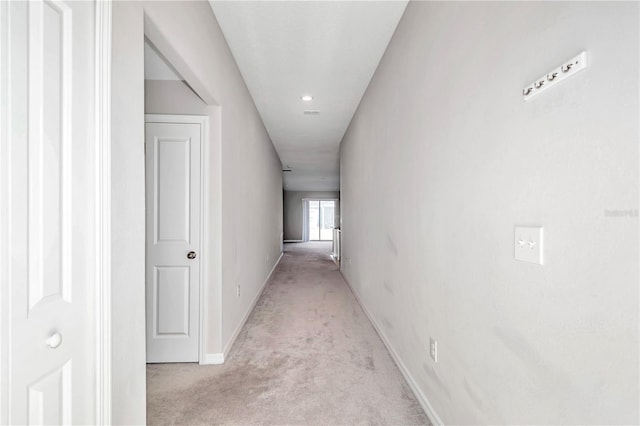hallway featuring light carpet and baseboards