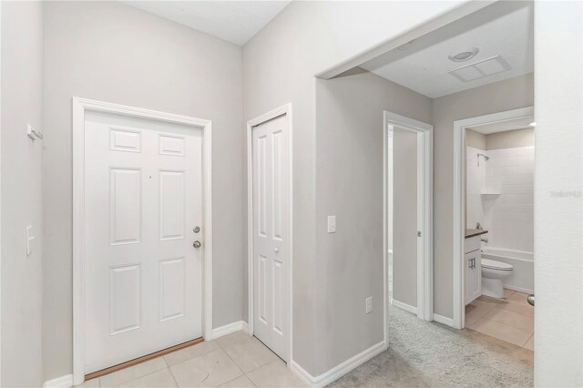 foyer with light tile patterned flooring and baseboards