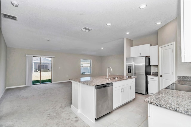 kitchen with stainless steel appliances, a sink, white cabinetry, an island with sink, and a textured ceiling