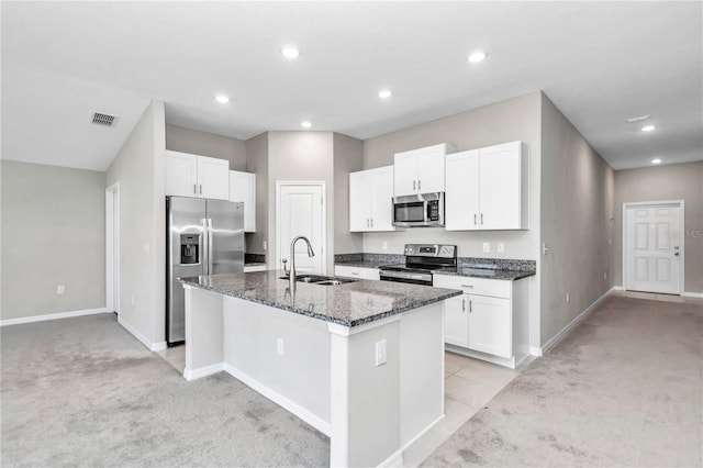 kitchen featuring a sink, appliances with stainless steel finishes, light colored carpet, dark stone countertops, and baseboards