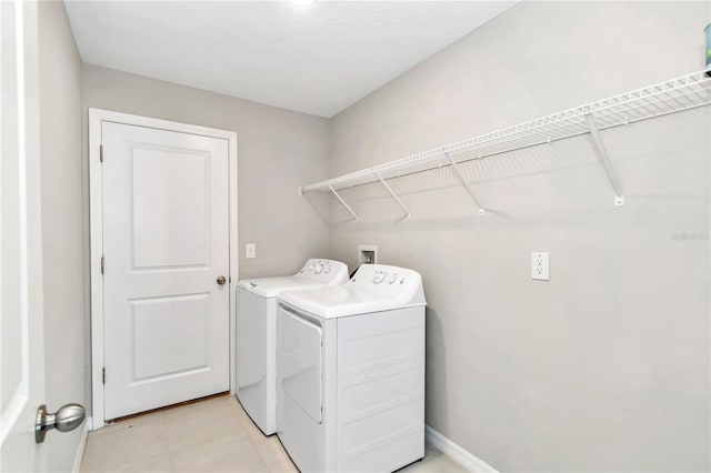 clothes washing area with independent washer and dryer and baseboards