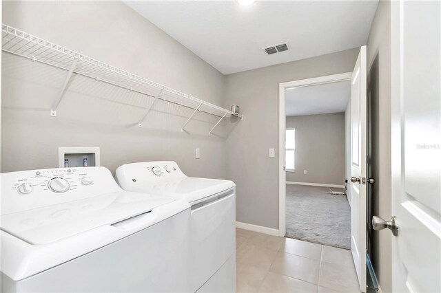 laundry room featuring washer and dryer, baseboards, light carpet, and light tile patterned floors
