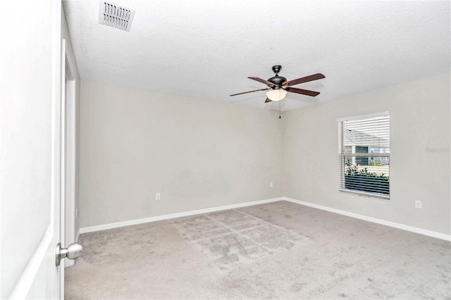 carpeted spare room with a ceiling fan, baseboards, and a textured ceiling
