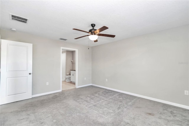 unfurnished bedroom featuring carpet, baseboards, ensuite bath, and ceiling fan