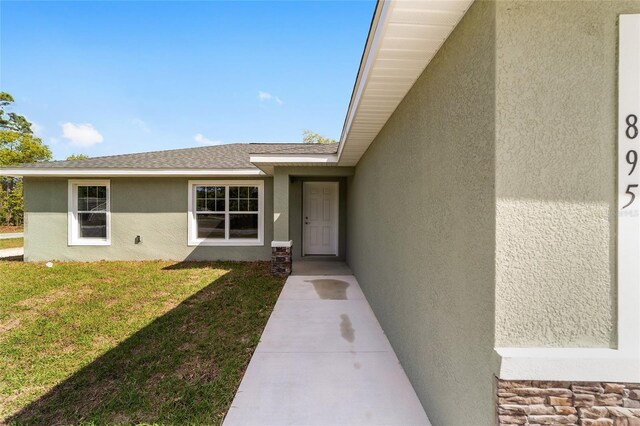 25 Juniper Pass Way, Ocala, FL 34480 - property entrance with stucco siding, a yard, and roof with shingles
