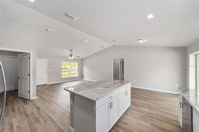 25 Juniper Pass Way, Ocala, FL 34480 - kitchen with vaulted ceiling, stainless steel dishwasher, white cabinets, light stone countertops, and light wood finished floors