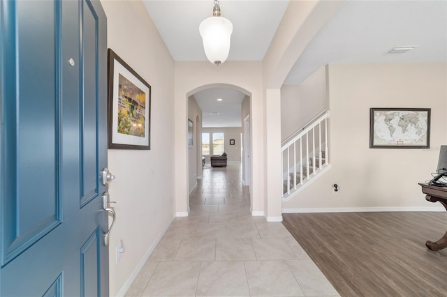 5653 SW 50th Ter, Ocala, FL 34474 - foyer featuring arched walkways, stairway, baseboards, and light tile patterned flooring