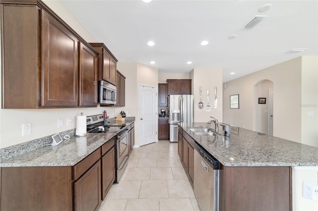 5653 SW 50th Ter, Ocala, FL 34474 - kitchen featuring appliances with stainless steel finishes, a sink, arched walkways, a kitchen island with sink, and light stone counters
