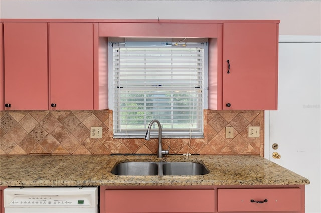 kitchen featuring red cabinets, a sink, dishwasher, and backsplash