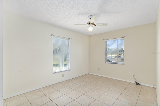 unfurnished room with ceiling fan, a textured ceiling, light tile patterned flooring, and baseboards