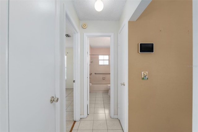 hallway with light tile patterned floors and a textured ceiling