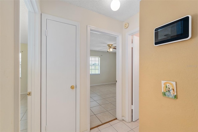 hall with a textured ceiling and light tile patterned floors