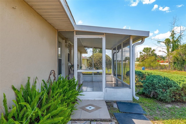 view of exterior entry featuring stucco siding and fence