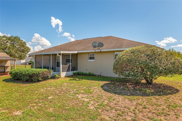 back of house featuring a sunroom, a lawn, and stucco siding