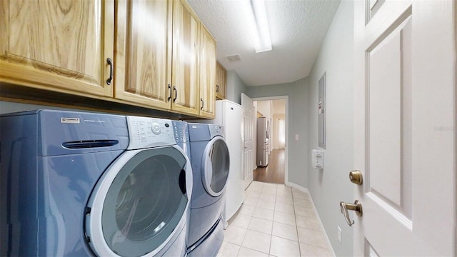 10528 SW 27th Ave, Ocala, FL 34476 - laundry room with washing machine and dryer, cabinet space, light tile patterned flooring, baseboards, and a textured ceiling