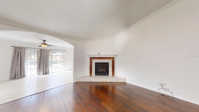 10528 SW 27th Ave, Ocala, FL 34476 - unfurnished living room with a ceiling fan, a fireplace, arched walkways, ornamental molding, and wood finished floors