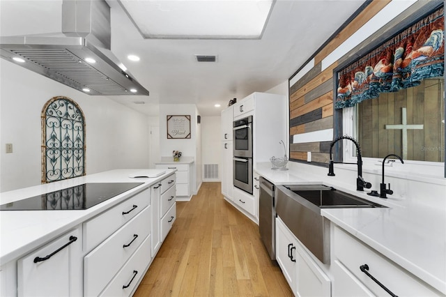 2146 NE 9th St, Ocala, FL 34470 - kitchen with wall chimney range hood, a sink, appliances with stainless steel finishes, white cabinets, and recessed lighting
