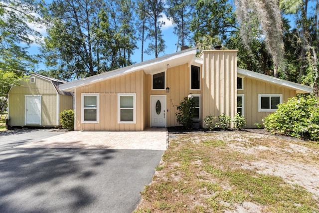 3728 S Eastpark Way, Homosassa, FL 34446 - mid-century modern home featuring a storage shed, an outbuilding, asphalt driveway, and board and batten siding