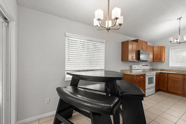 3728 S Eastpark Way, Homosassa, FL 34446 - kitchen with white electric range, a chandelier, brown cabinetry, light tile patterned floors, and vaulted ceiling