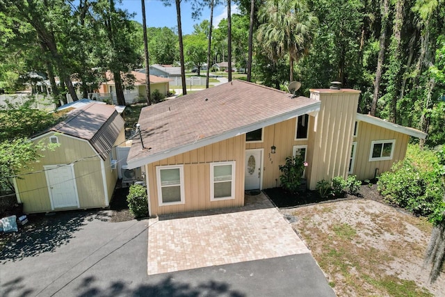 3728 S Eastpark Way, Homosassa, FL 34446 - mid-century home with a storage shed, a shingled roof, an outbuilding, and board and batten siding