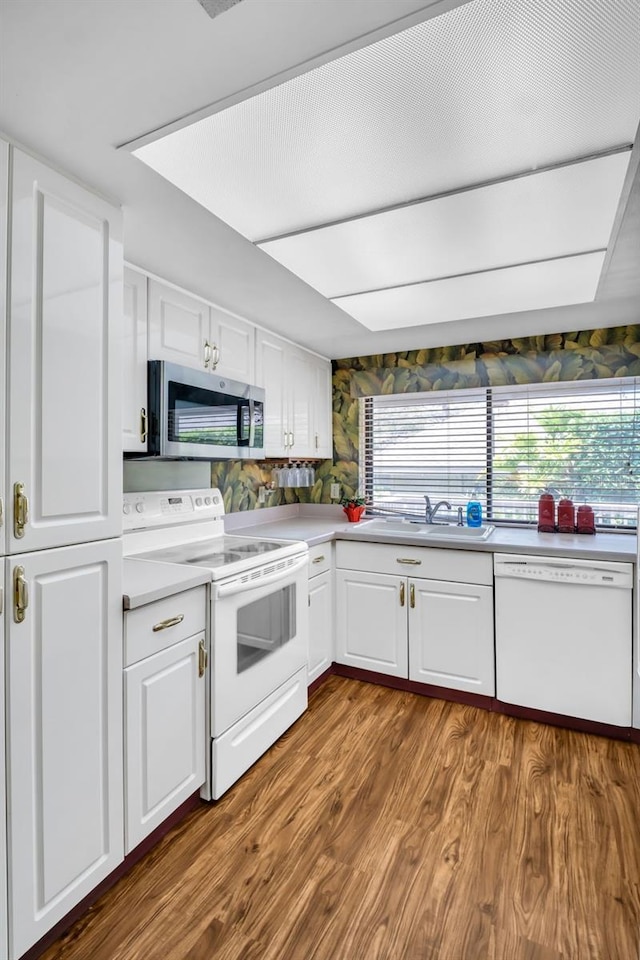 1001 Old Mill Pond Rd, Palm Harbor, FL 34683 - kitchen with white appliances, a sink, white cabinets, dark wood-style flooring, and light countertops