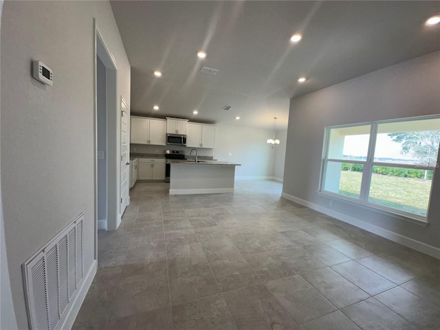 15106 SE 94th Ter, Summerfield, FL 34491 - kitchen with stainless steel appliances, a sink, baseboards, dark countertops, and a kitchen island with sink