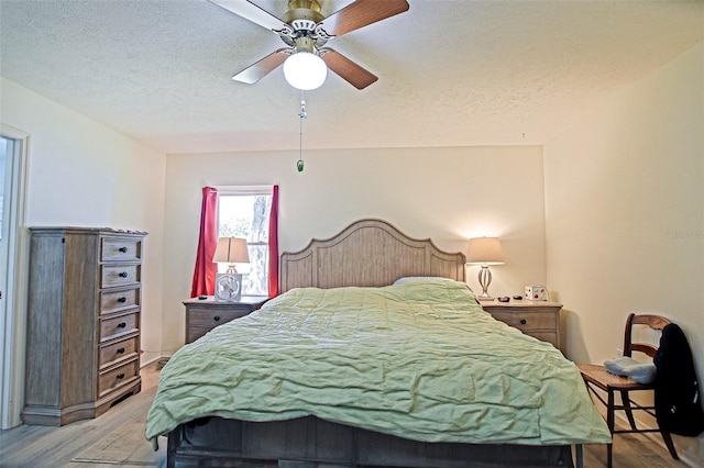 bedroom with light wood finished floors, a textured ceiling, and a ceiling fan