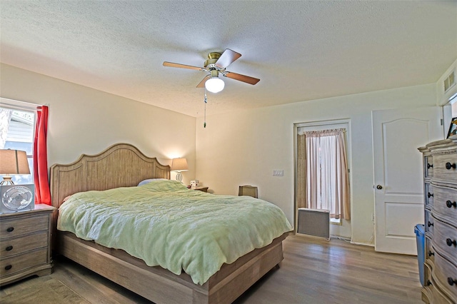 bedroom with wood finished floors, a textured ceiling, and a ceiling fan