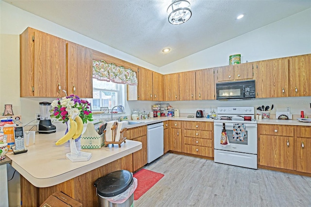 kitchen with white appliances, a sink, lofted ceiling, light countertops, and light wood-style floors