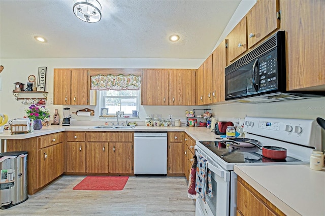 kitchen featuring white appliances, a sink, light wood-type flooring, light countertops, and recessed lighting