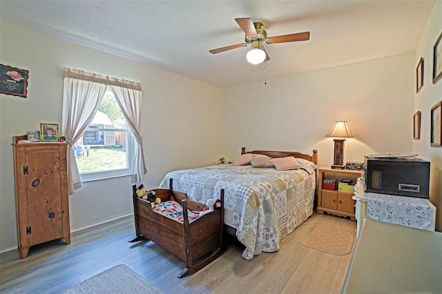 bedroom with light wood-style flooring, ceiling fan, and baseboards